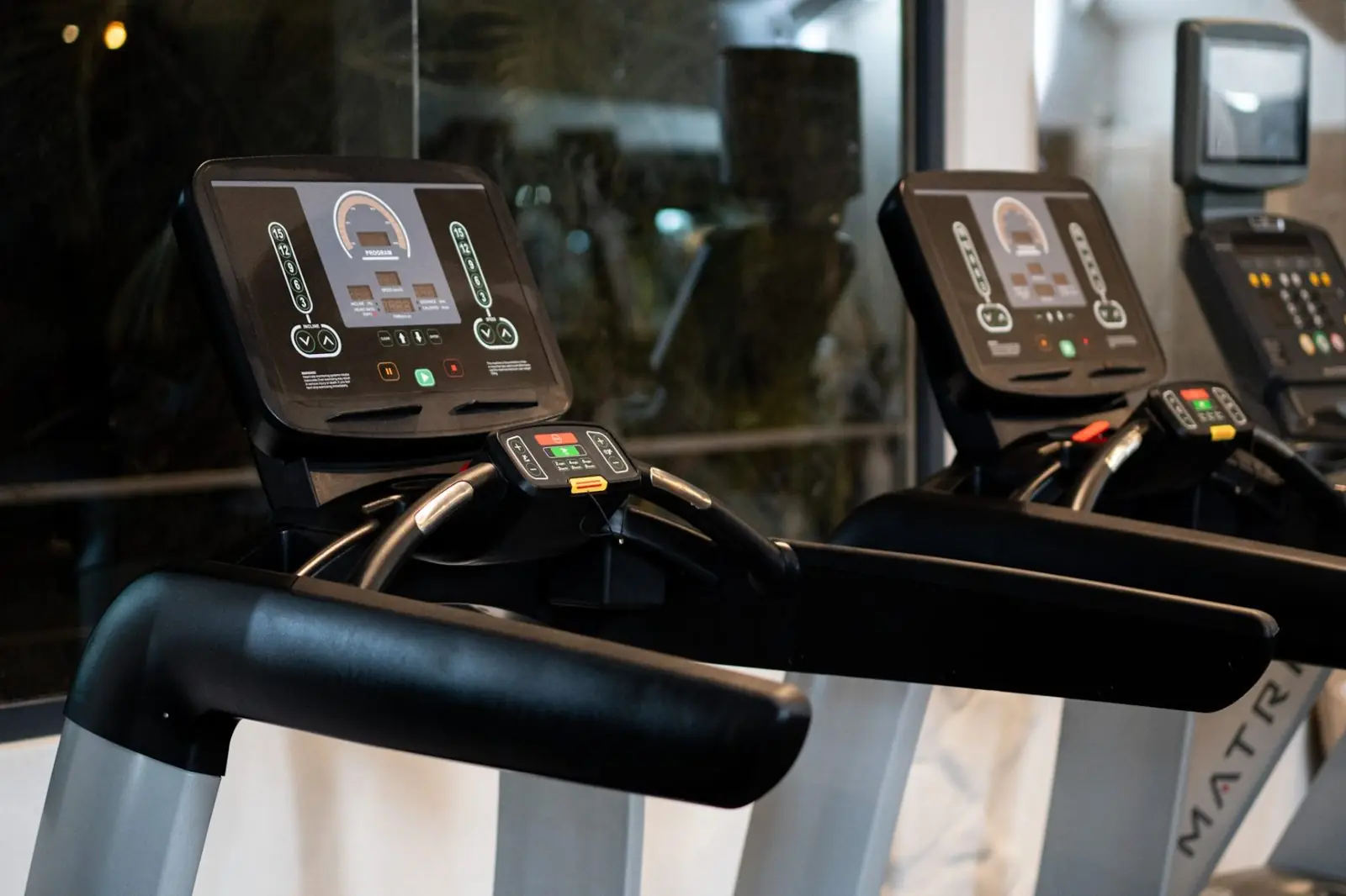 Gimnasio de hotel con caminadoras Matrix junto a ventanal — equipamiento para hospitality premium