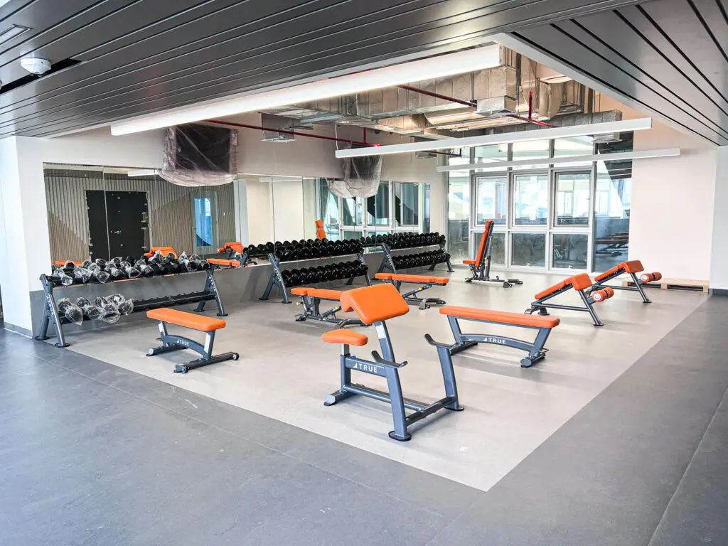 Sala de fuerza universitaria True Fitness con bancos naranja y mancuernas — Fitness Factory